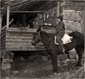 Horsewomen giving book to Appalachian cabin dweller.