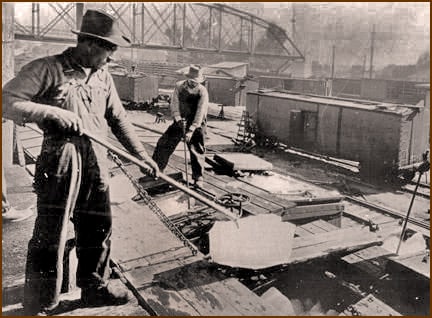 1930s workmen load blocks of ice into the top of rail cars carrying perishable produce.