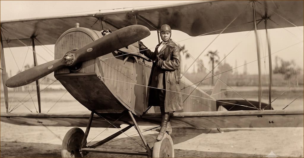 Bessie Coleman standing on the wheel of her plane